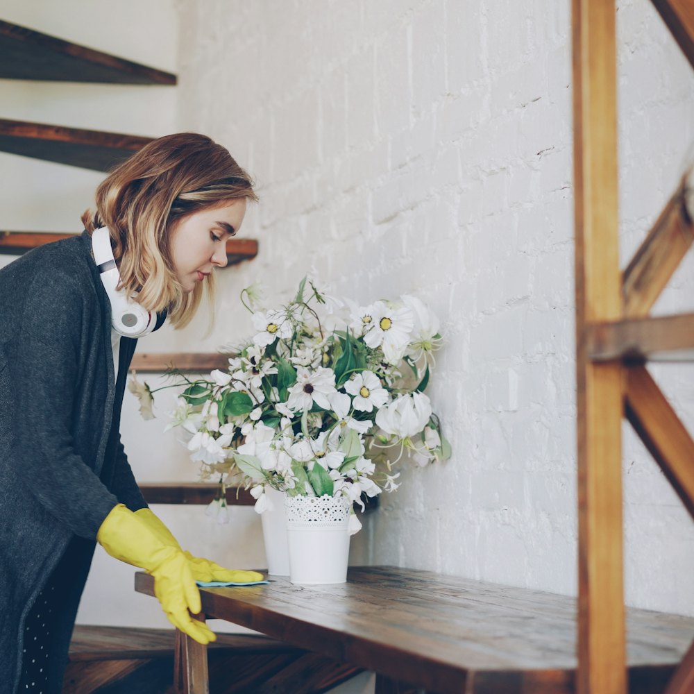 A cleaner in yellow gloves dusting a wooden side table